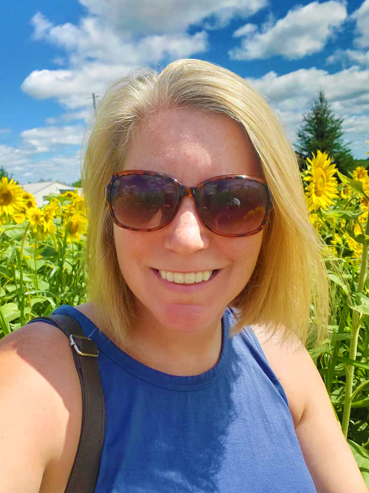 Carla - Baker and Owner - Sunflower Sweets Owner - In Sunflower field.  Sunglasses.